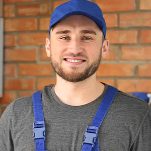 Professional plumber in uniform holding pipe wrench